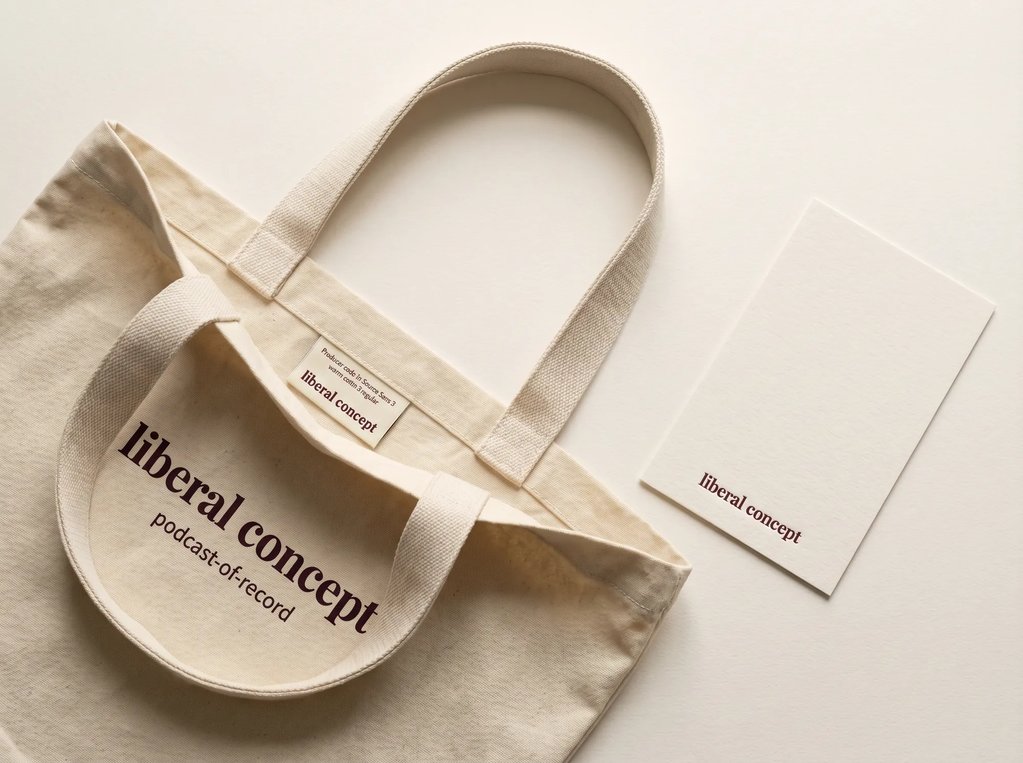 Liberal Concept Cohort Tote (Cultural Podcast Network) — A heavy waxed-cotton cohort tote in warm cream with the wordmark screen-printed in deep wine at the strap base — issued to working podcast members and named producers at the working release.