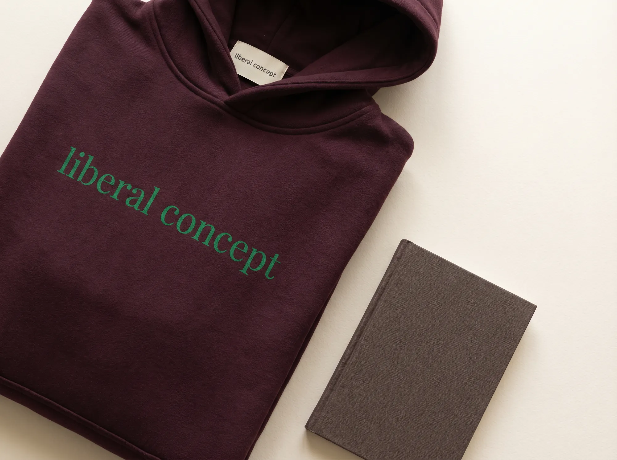 Liberal Concept Cohort Hoodie (Apparel) — A heavy fleece cohort hoodie in deep wine with the wordmark screen-printed in forest green across the chest — issued to working platform members and named cohort leads at the working seminar close.